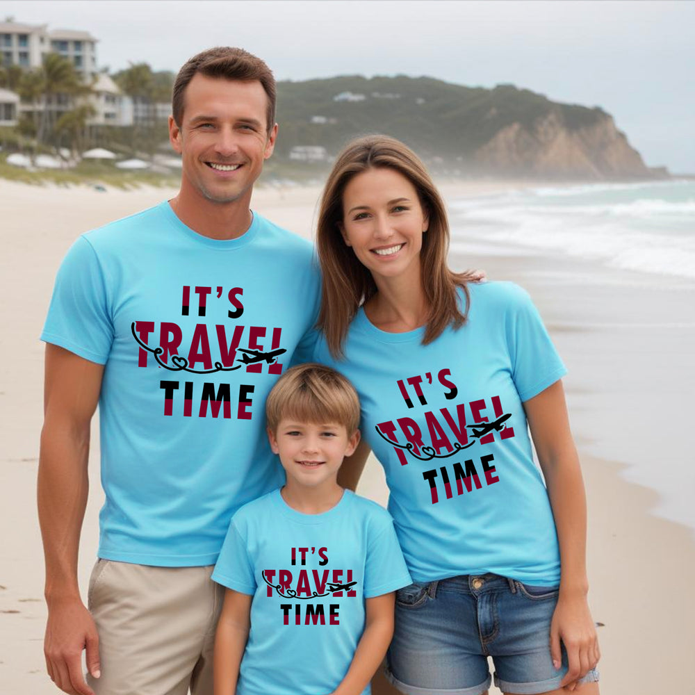 Family of three on a beach wearing matching blue t-shirts with 'It's Travel Time' text.