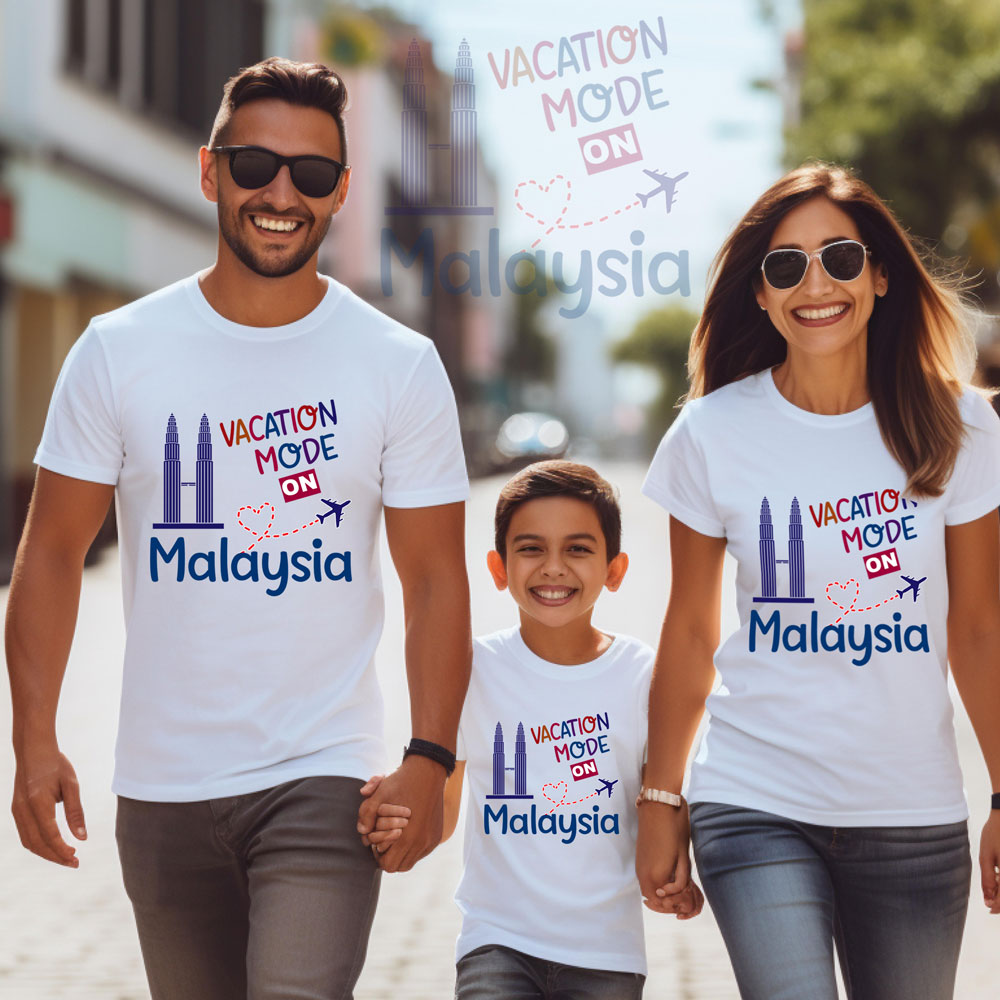 Family wearing matching 'Vacation Mode on Malaysia' t-shirts on a street.