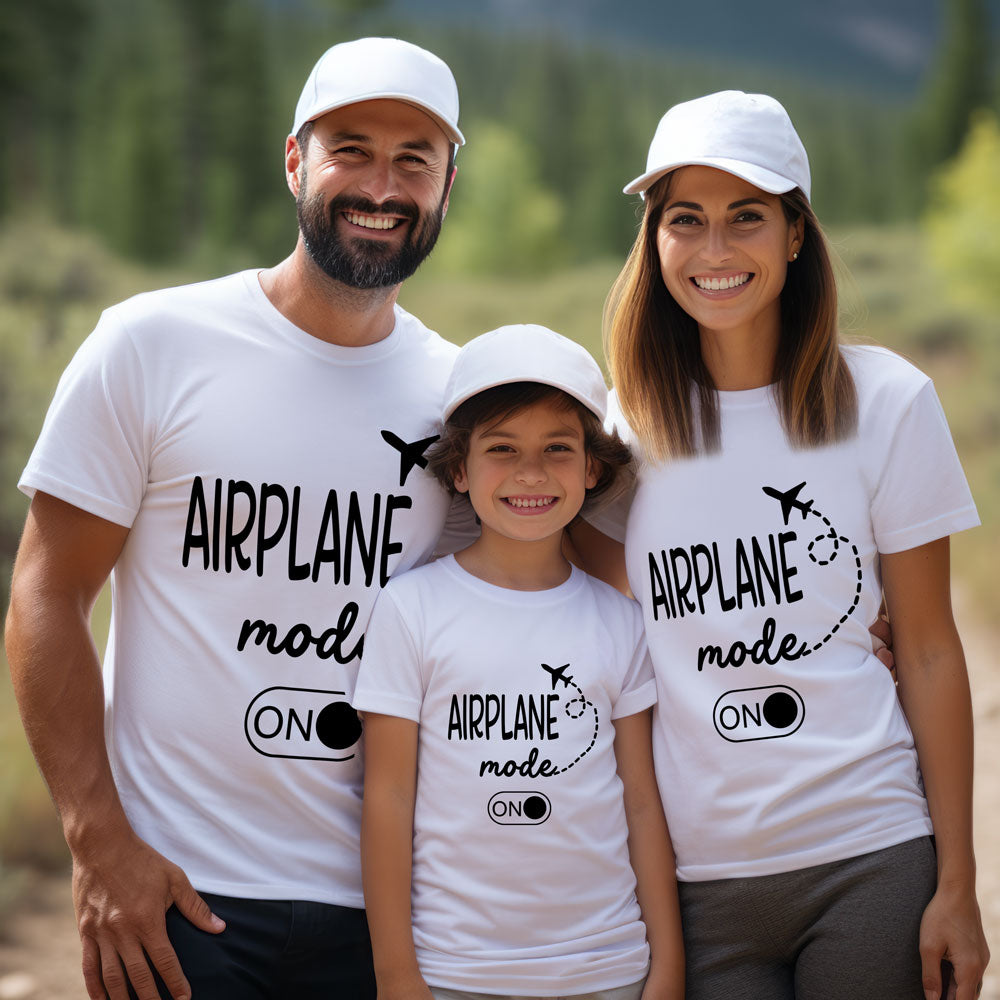 Family of three wearing white t-shirts with 'Airplane mode on' text, standing outdoors.