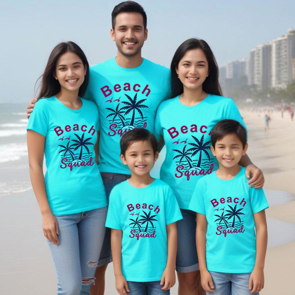 Family of five wearing matching blue t-shirts with 'Beach Squad' text and palm tree graphics on a beach.