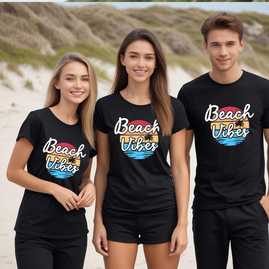 Three people wearing black 'Beach Vibes' t-shirts on a beach.