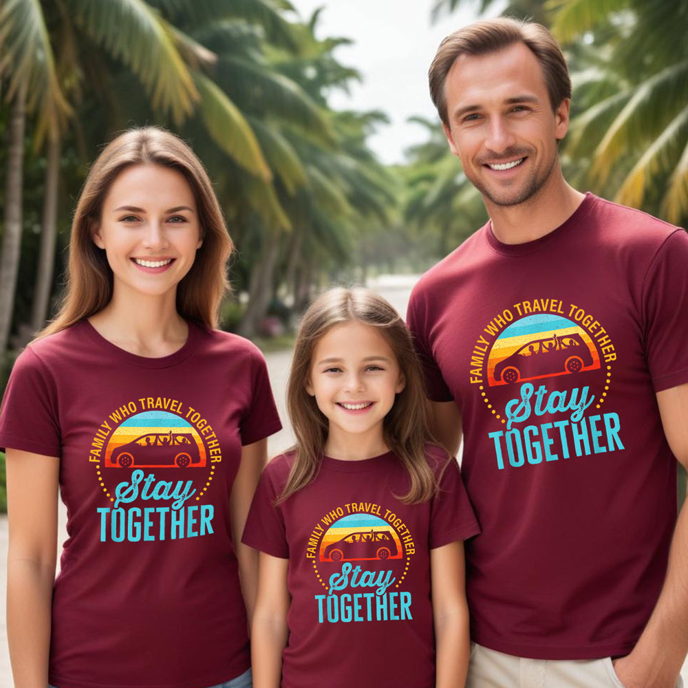 Family of three wearing matching maroon t-shirts with a travel-themed design in a tropical setting.