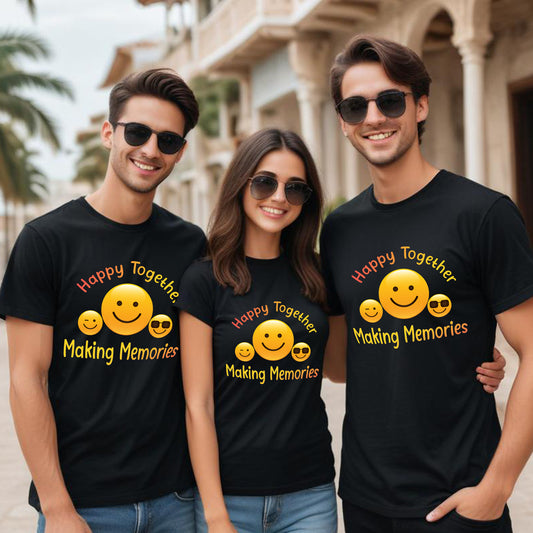 Three people wearing black t-shirts with smiley faces and text, standing together outdoors.