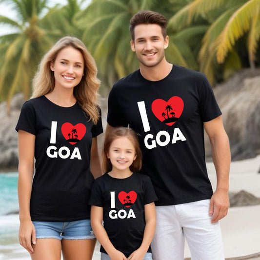 Family of three wearing 'I ❤️ Goa' t-shirts on a beach with palm trees in the background.