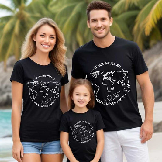 Family of three wearing matching black t-shirts with world map design and text on a beach.
