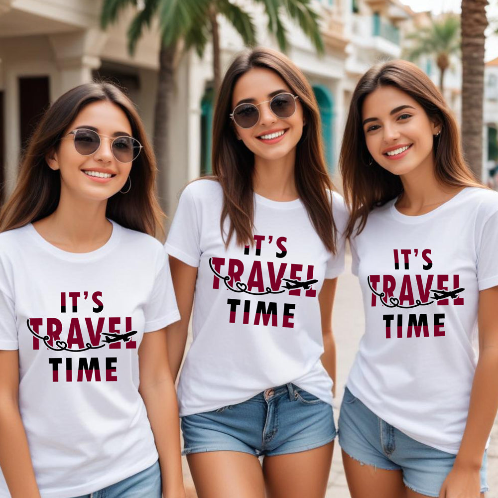 Three women wearing white t-shirts with 'It's Travel Time' text, standing outdoors.