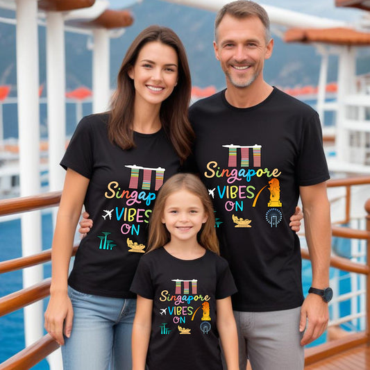 Family of three wearing black t-shirts with 'Singapore Vibes On' design on a cruise ship deck.