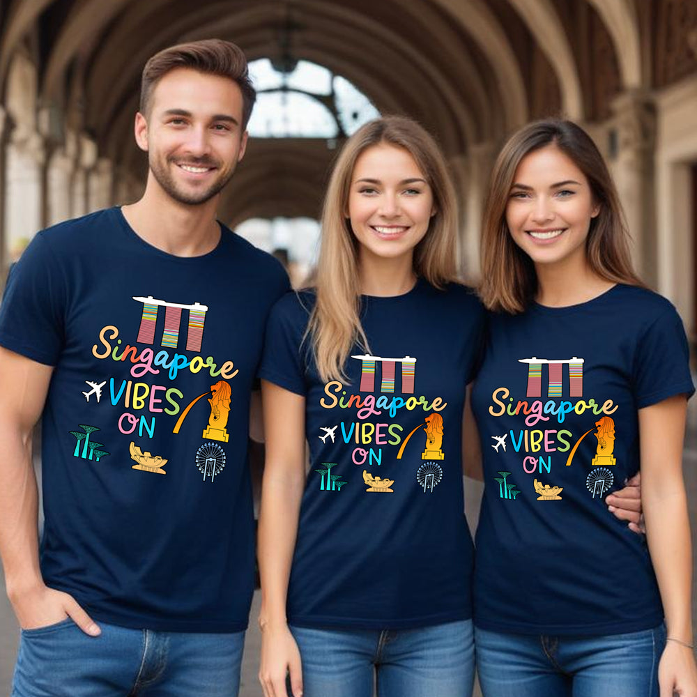 Three people wearing navy blue t-shirts with 'Singapore Vibes On' text and colorful graphics.